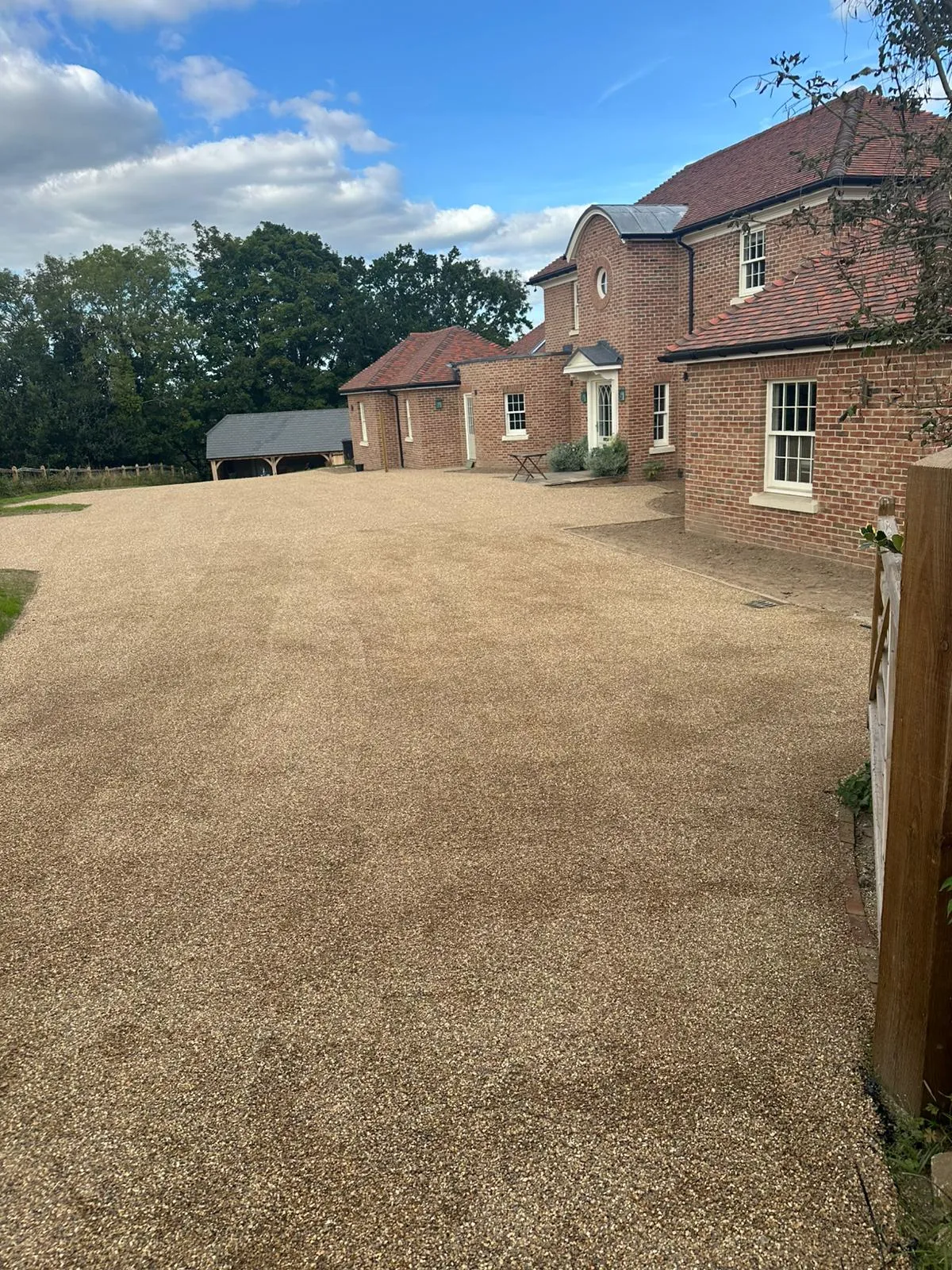 A gravel driveway with a house in the background.